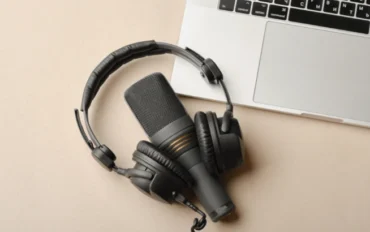 Composição plana com microfone para podcasts e fones de ouvido de estúdio pretos em fundo marrom com café e laptop aprendendo conceito de educação onlinexa boyarkinamarina