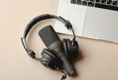 Composição plana com microfone para podcasts e fones de ouvido de estúdio pretos em fundo marrom com café e laptop aprendendo conceito de educação onlinexa boyarkinamarina