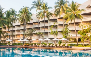 Foto: lifeforstock no Freepik | fachada de hotel com palmeiras, piscina e cadeiras de descanso | Marketing digital para hotelaria