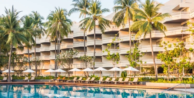 Foto: lifeforstock no Freepik | fachada de hotel com palmeiras, piscina e cadeiras de descanso | Marketing digital para hotelaria