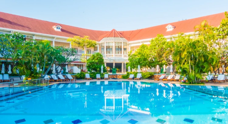 Foto: mrsiraphol no Freepik | fachada de hotel com palmeiras, piscina e cadeiras de descanso | Marketing digital para hotelaria